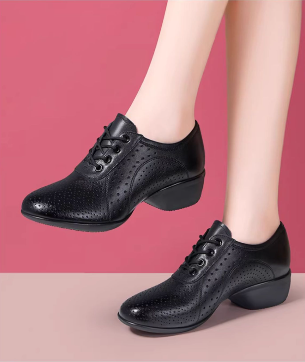 Close-up view of black leather dance shoe showing star-shaped perforations and lace-up front
