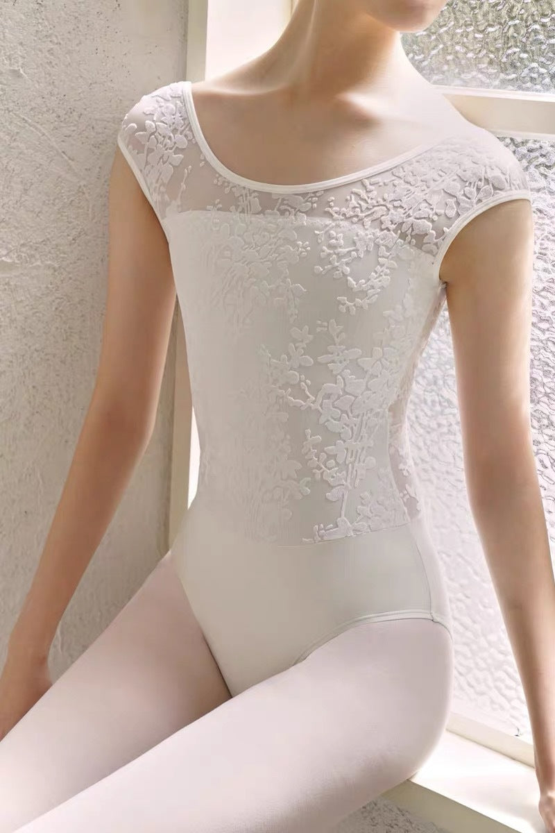 Model wearing white ballet leotard, sitting by the window, elegant training dancewear